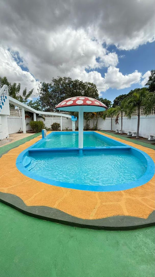 Piscina principal con hongo decorativo rojo y área infantil